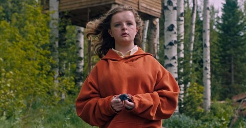 Charlie, from Hereditary, stands in a forest. 